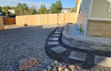 Backyard with gravel ground, a stepping stone path, and a wooden fence.